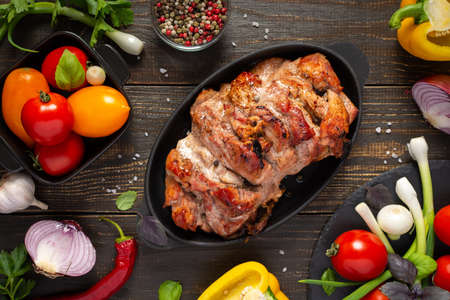 Baked pork ham on a wooden background, fried piece of meat with spices, fresh vegetables, top viewの写真素材