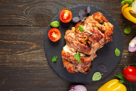 Baked pork ham on a wooden background, fried piece of meat with spices, fresh vegetables, top viewの写真素材
