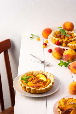 Open pie from shortcrust pastry with peaches, peach clafoutis on white tableの写真素材