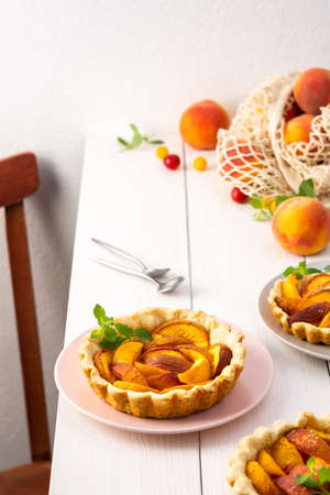 Open pie from shortcrust pastry with peaches, peach clafoutis on white tableの写真素材