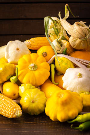 Fresh harvest of zucchini and pattypan squash, yellow squash and corn cob and pepper on wooden backgroundの写真素材