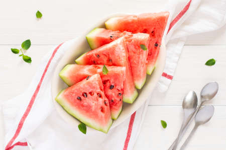 Juicy ripe sweet red watermelon slices with mint in a plate on a white backgroundの写真素材