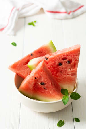 Juicy ripe sweet red watermelon slices with mint in a plate on a white backgroundの写真素材