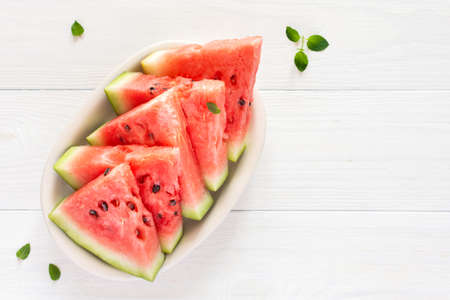 Juicy ripe sweet red watermelon slices with mint in a plate on a white background, top viewの写真素材