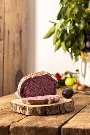 Blueberry and plum bread on a wooden background, berries and fruits on the table, plum branches in a vase, rustic interiorの写真素材