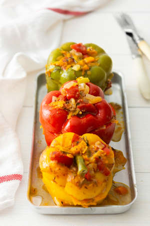 Meat and rice stuffed multicolored bell peppers with hats and vegetables closeupの写真素材