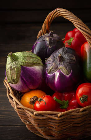 Fresh autumn harvest of organic vegetables, bell peppers with tomatoes, eggplant and pumpkin, vegetables in a wicker basketの写真素材