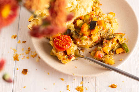 Pie with vegetables in a plate, zucchini with eggplants and tomatoes, potatoes with carrots and onions, yeast dough with pre-stewed vegetables and cheese baked in the ovenの写真素材
