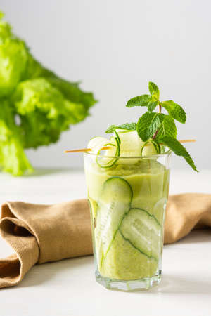 Broccoli and cucumber smoothie, delicious healthy drink made from green vegetables, a glass of smoothies on a white background, garnish of cucumbers and mintの写真素材