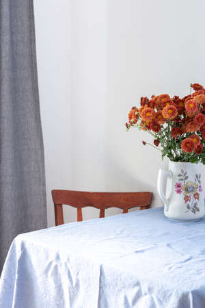 Home interior, table with blue tablecloth, vase with autumn flowers chrysanthemumsの写真素材