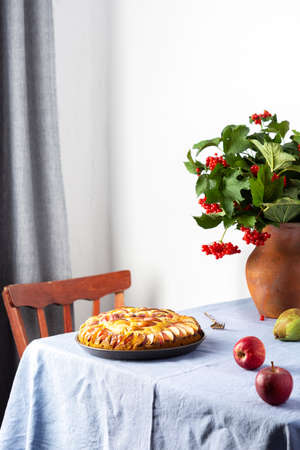 Delicious apple pie, home interior, table with blue tablecloth, vase with autumn flowers chrysanthemumsの写真素材