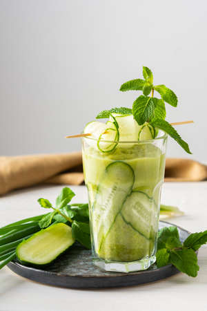 Broccoli and cucumber smoothie, delicious healthy drink made from green vegetables, a glass of smoothies on a white background, garnish of cucumbers and mintの写真素材