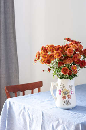 Home interior, table with blue tablecloth, vase with autumn flowers chrysanthemumsの写真素材