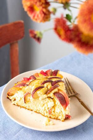 Delicious apple pie, a serving of apple pie on a plate with a fork, home interior, table with blue tablecloth, vase with autumn flowers chrysanthemumsの写真素材