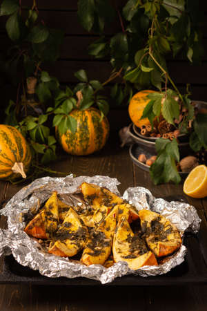 Baked pumpkin, pieces of pumpkin with dill and parsley, spices and lemon juice baked in foil in the ovenの写真素材