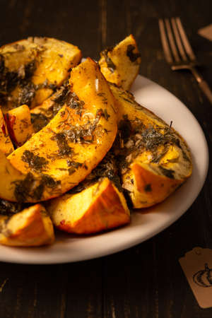 Baked pumpkin in a plate, pieces of pumpkin with dill and parsley, spices and lemon juice baked in foil in the ovenの写真素材