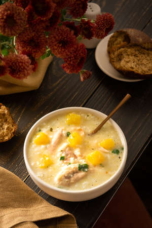 Chicken, rice and pumpkin soup in a plate with a spoon, delicious lunch or breakfast, flowers in a vase, bread and hodgepodgeの写真素材