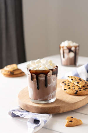 Milkshake with ice cream, marshmallows and chocolate, a glass with a milkshake on a wooden board, chocolate chip cookiesの写真素材