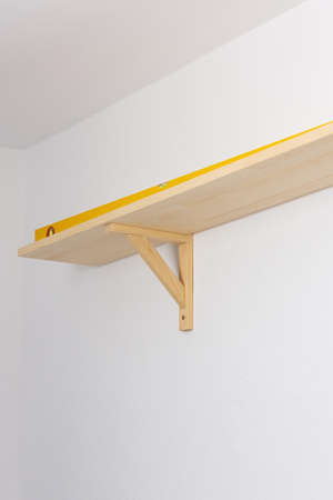 The process of fixing the wooden shelf to the wall, the level tool checks the evenness of the shelfの写真素材