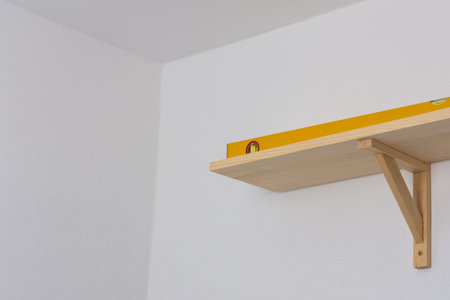 The process of fixing the wooden shelf to the wall, the level tool checks the evenness of the shelf