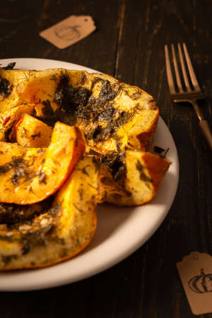 Baked pumpkin in a plate, pieces of pumpkin with dill and parsley, spices and lemon juice baked in foil in the ovenの写真素材
