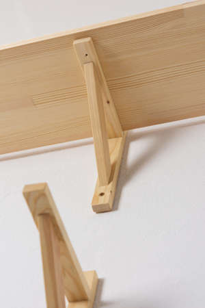 The process of attaching a wooden shelf to the wall, shelf corners together with a bookshelfの写真素材