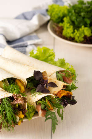 Tortillas with arugula, baked pumpkin and dill, prosciutto and basil, salad and young parmesanの写真素材
