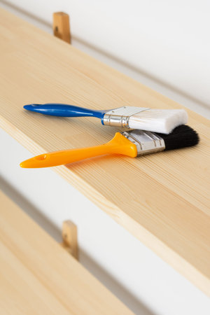 Paint brushes are on a wooden shelf, the process of varnishing or painting the shelvesの写真素材