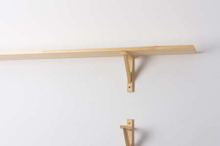 The process of attaching a wooden shelf to the wall, shelf corners together with a bookshelfの写真素材