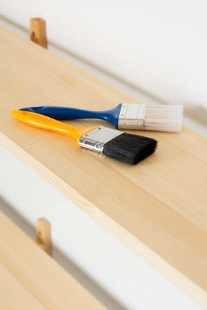 Paint brushes are on a wooden shelf, the process of varnishing or painting the shelvesの写真素材