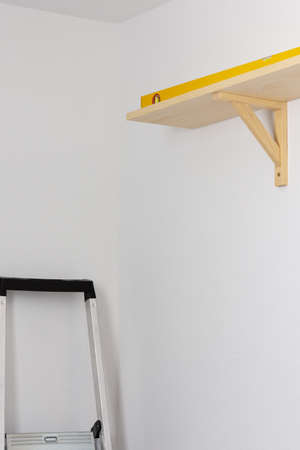 The process of fixing the wooden shelf to the wall, the level tool checks the evenness of the shelfの写真素材