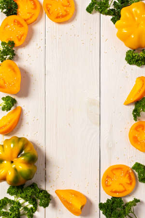 Yellow tomatoes with bell peppers and sesame seeds on white wooden background, top viewの写真素材
