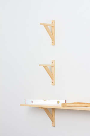 The process of fixing the wooden shelf to the wall, the level tool checks the evenness of the shelfの写真素材