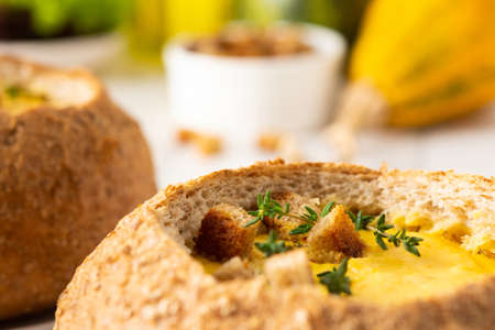 Pumpkin puree soup in a plate of bread, pumpkin soup with thyme , cheese and croutons on a white wooden backgroundの写真素材