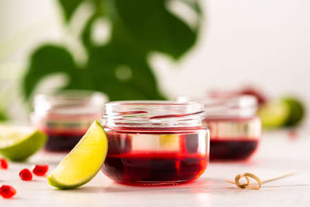 Red alcoholic shots on white background , small jars with liquor and grenadine with limeの写真素材
