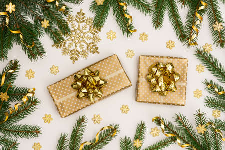 Festive background with gold decoration , green spruce branches and shiny golden serpentine confetti, golden gift boxes with bow ,glittering snowflakes , flat lay, top viewの写真素材