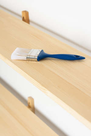 Paint brush on a wooden shelf, the process of varnishing or painting the shelvesの写真素材