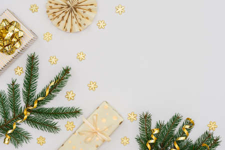 Festive background with gold decoration , green spruce branches and golden gift boxes with bow ,glittering snowflakes and paper christmas tree decorations , flat lay, top viewの写真素材