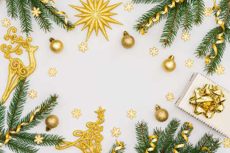 Festive background with gold decoration, green spruce branches and shiny golden serpentine confetti, golden deer and gift boxes, glittering snowflakes, flat lay, top view, copy spaceの写真素材