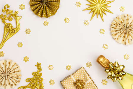 Festive background with gold decoration , gift box with bottle of sparkling wine, shiny golden serpentine confetti and paper christmas tree decorations, glittering snowflakes and christmas treeの写真素材