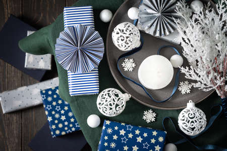 Christmas composition in white ,green and blue shades, christmas balls and candle, gift boxes and snowflakes, decorative white spruce branches and snowball on a green tablecloth, top viewの写真素材