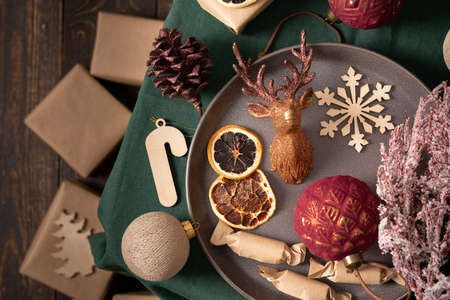Christmas or new year background, balls and homemade candy, dried fruits and decorative deer , spruce and cotoneaster branches on a green tablecloth,gifts in craft paper, top viewの写真素材