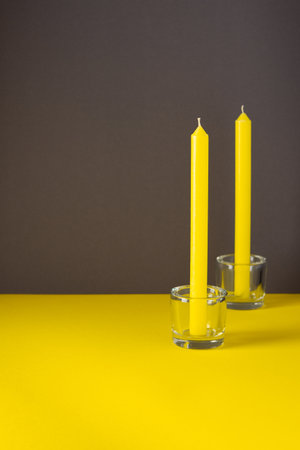 Yellow tall candles in a glass candlesticks, trendy colors of the year, yellow and gray backgroundの写真素材