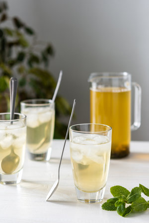 Cold refreshing green tea with ice and mint, tea jug and glasses on white wooden backgroundの写真素材
