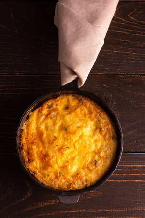 Frittata with cheese, mozzarella and stewed pumpkin in a cast iron pan on a wooden backgroundの写真素材