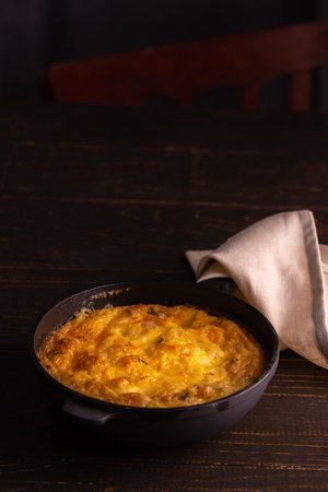 Frittata with cheese, mozzarella and stewed pumpkin in a cast iron pan on a wooden backgroundの写真素材
