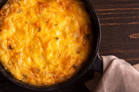 Frittata with cheese, mozzarella and stewed pumpkin in a cast iron pan on a wooden backgroundの写真素材