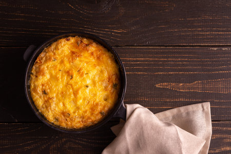 Frittata with cheese, mozzarella and stewed pumpkin in a cast iron pan on a wooden backgroundの写真素材