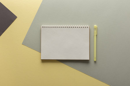 Open spiral notepad on gray and yellow background , notebook and pen lie on textural paper, flat lay concept in trendy colors of the year yellow and grayの写真素材