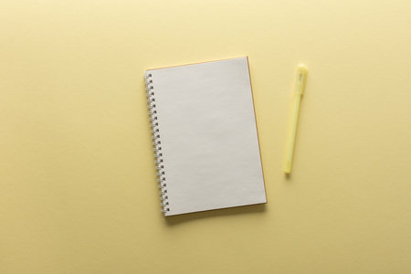 Open spiral notepad on yellow background , notebook and pen lie on textural paper, flat lay concept in trendy colors of the yearの写真素材